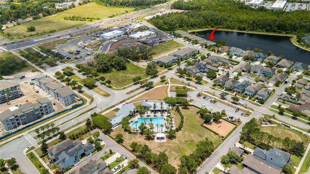 This aerial view shows a residential community featuring a swimming pool, pond, and surrounding houses — 2443 PORTICO STREET, ODESSA, FL