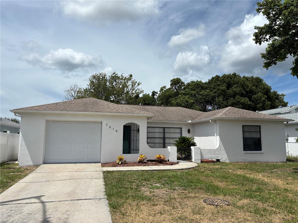An aerial view shows a single-story house with a large tree beside a lake — 7619 VIENNA LANE, PORT RICHEY, FL