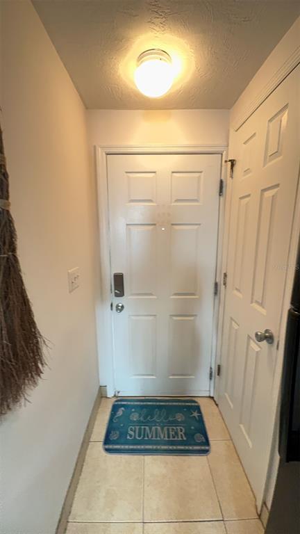 A small entryway features a white door, a tiled floor, and a blue summer rug — 108 5TH STREET UNIT 1A, FLAGLER BEACH, FL