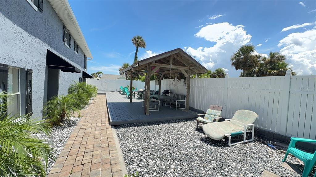 A gray house exterior features a brick walkway leading to a wooden deck with a gazebo — 108 5TH STREET UNIT 1A, FLAGLER BEACH, FL