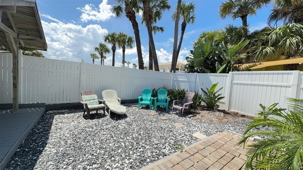 A fenced backyard features a gravel ground, a brick patio section, and several outdoor chairs — 108 5TH STREET UNIT 1A, FLAGLER BEACH, FL