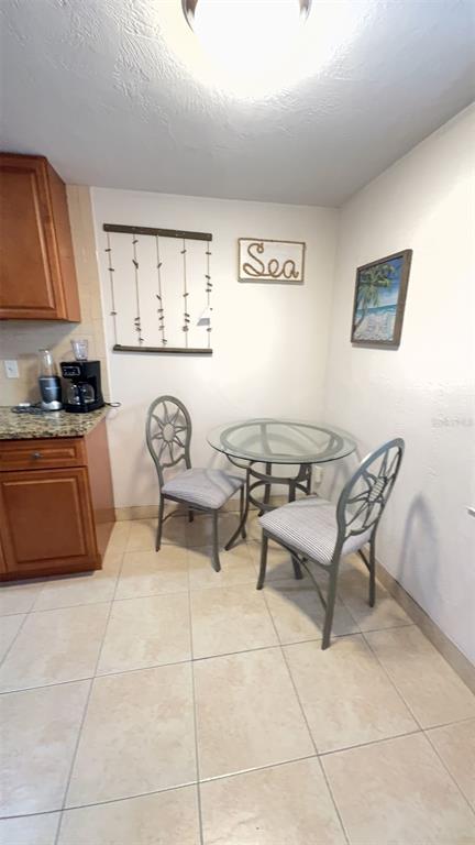 A small kitchen dining area features a glass-topped table, two chairs, and tiled flooring — 108 5TH STREET UNIT 1A, FLAGLER BEACH, FL