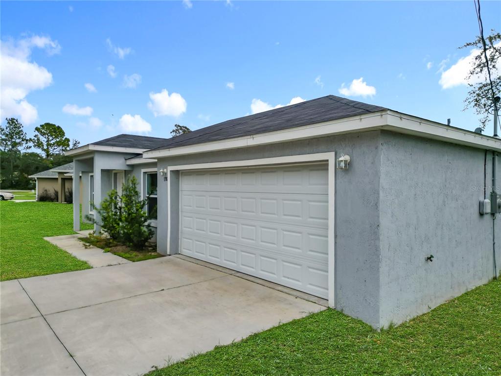 The exterior of a single-story house features a white garage door and a concrete driveway — 178 PINE COURSE, OCALA, FL