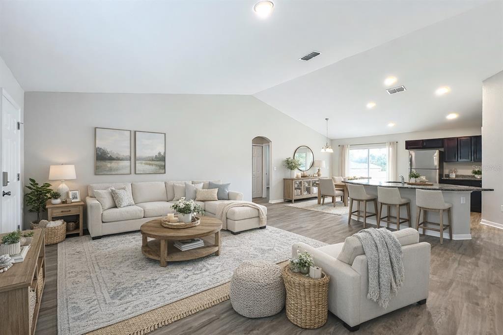 An open-concept living room and kitchen featuring light wood flooring and neutral furniture — 178 PINE COURSE, OCALA, FL