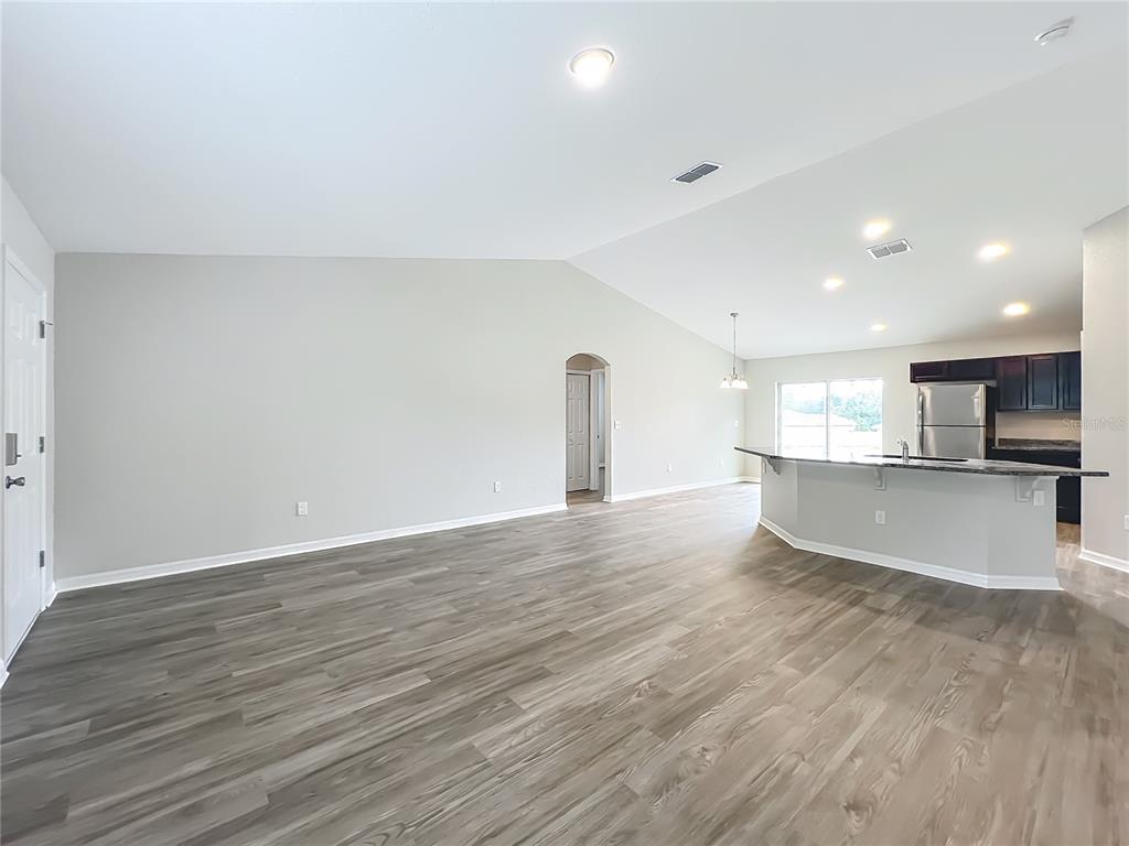 An open-concept living room features light gray walls, wood-look flooring, and a kitchen island — 178 PINE COURSE, OCALA, FL