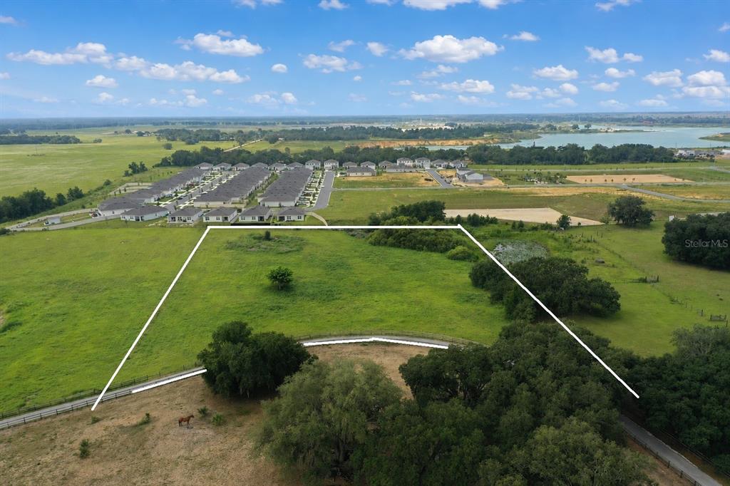 An aerial view shows a large, grassy plot of land outlined in white — 0 E HINSON AVENUE E, HAINES CITY, FL