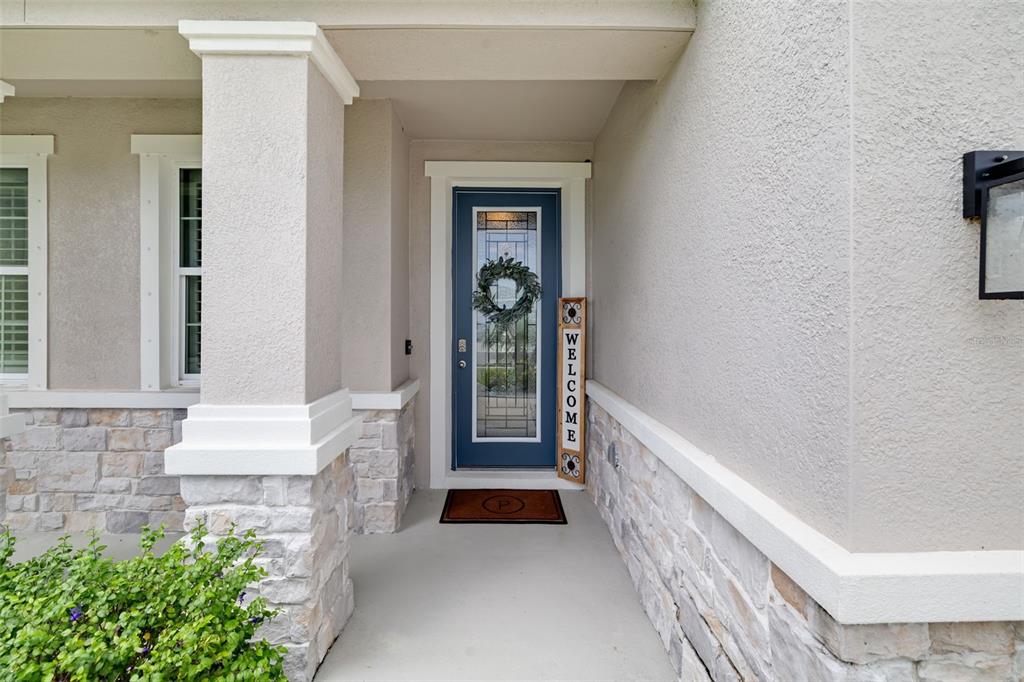 A covered entryway features a blue front door with a glass insert and stone siding — 15905 5TH AVENUE E, BRADENTON, FL
