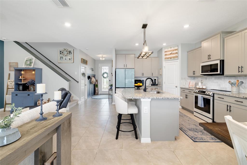 A modern kitchen features light gray cabinets, a granite island, and tile flooring — 15905 5TH AVENUE E, BRADENTON, FL