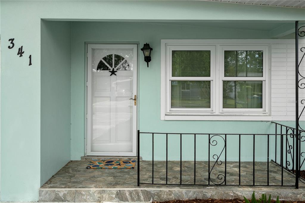 A light blue house exterior features a front door, a window, and a metal railing — 341 WERTZ DRIVE, LARGO, FL