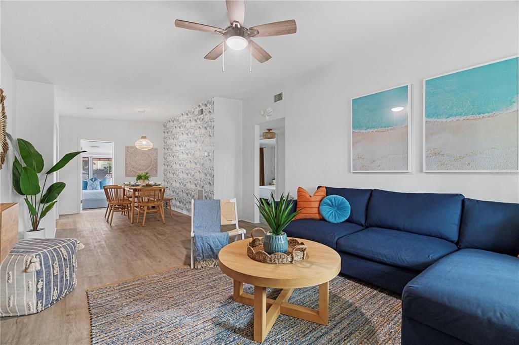 A living room features a blue sectional sofa, a round wooden coffee table, and dining area — 341 WERTZ DRIVE, LARGO, FL