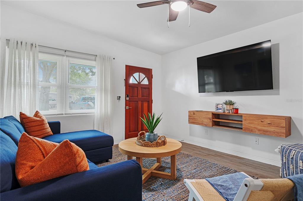 A living room features a blue sectional sofa, a round coffee table, and a wall-mounted television — 341 WERTZ DRIVE, LARGO, FL