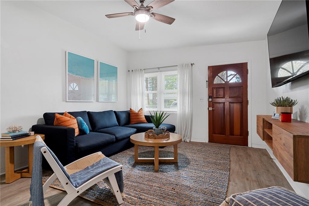 A living room features a navy sectional sofa, a wooden coffee table, and a front door — 341 WERTZ DRIVE, LARGO, FL
