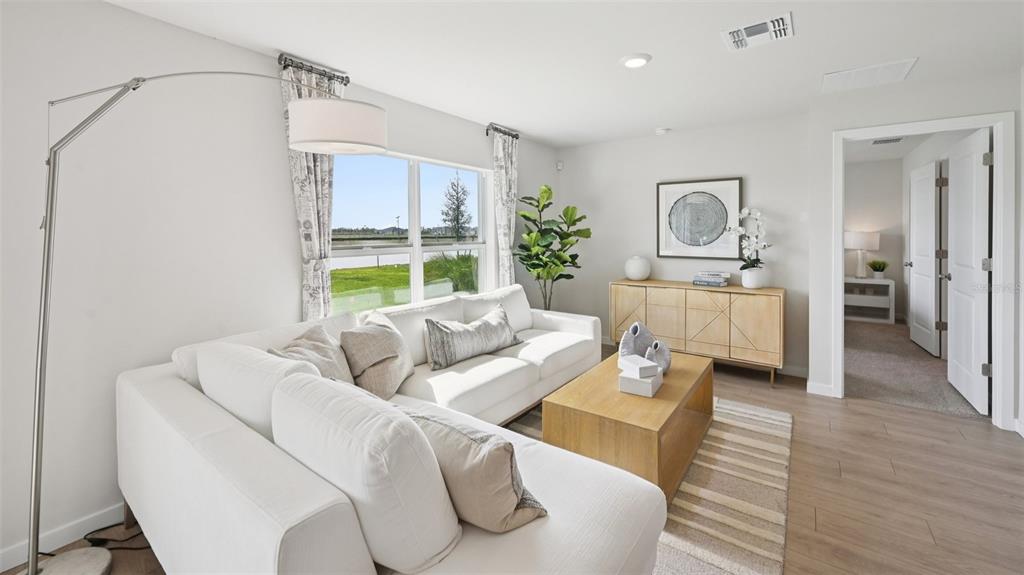A bright living room features a white sectional sofa, wood coffee table, and large windows — 1551 POWELL VALLEY DRIVE, PORT CHARLOTTE, FL