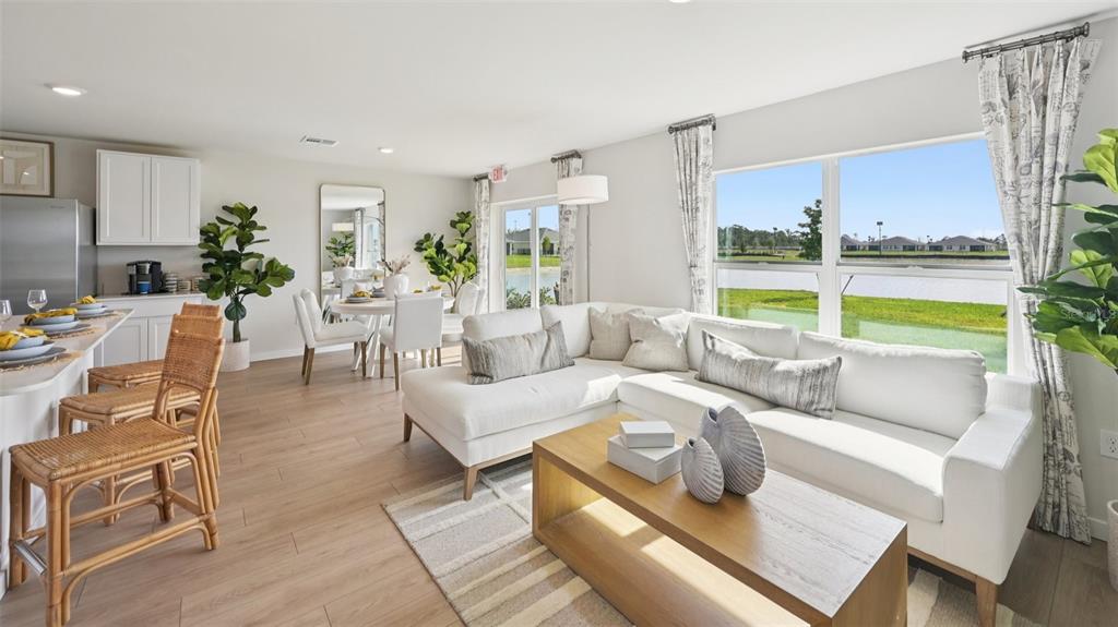 A bright living room and dining area feature light wood floors and a white sectional — 1551 POWELL VALLEY DRIVE, PORT CHARLOTTE, FL