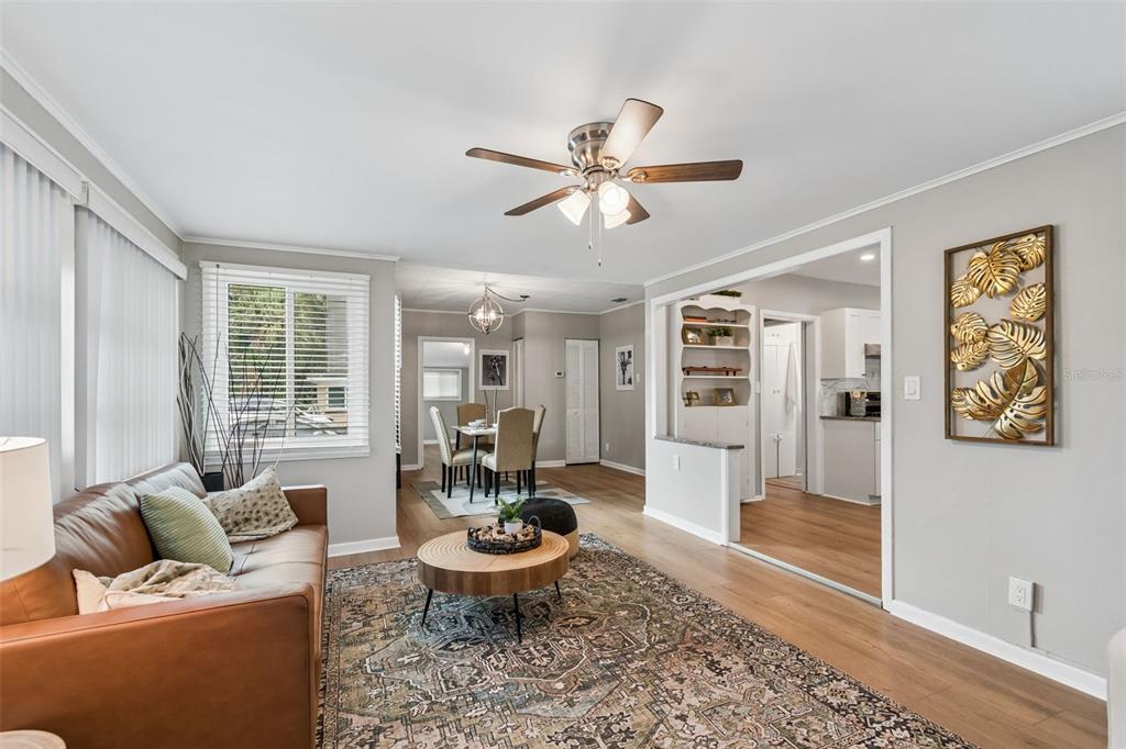 A living room with wood-look flooring, a leather sofa, and an open view to the dining area — 1004 WASHINGTON AVENUE, LARGO, FL
