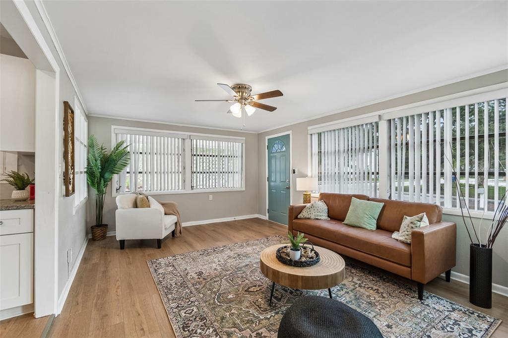 A living room features light wood flooring, a brown leather sofa, and a patterned area rug — 1004 WASHINGTON AVENUE, LARGO, FL