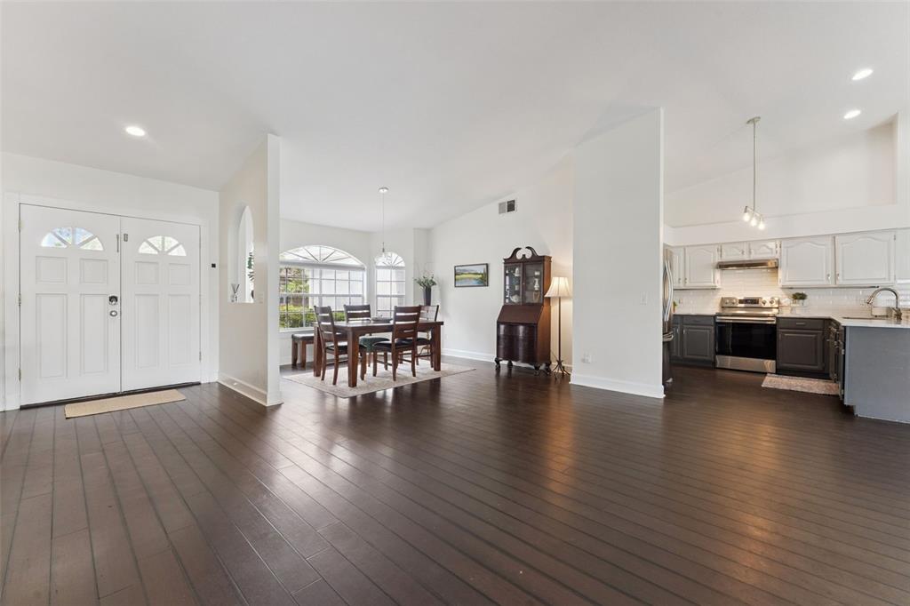 An open-concept living area features dark wood floors, a dining space, and a modern kitchen — 13627 DORNOCH DRIVE, ORLANDO, FL