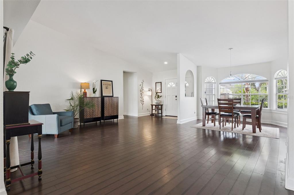 A spacious room with dark hardwood floors, a dining area, and a blue armchair — 13627 DORNOCH DRIVE, ORLANDO, FL