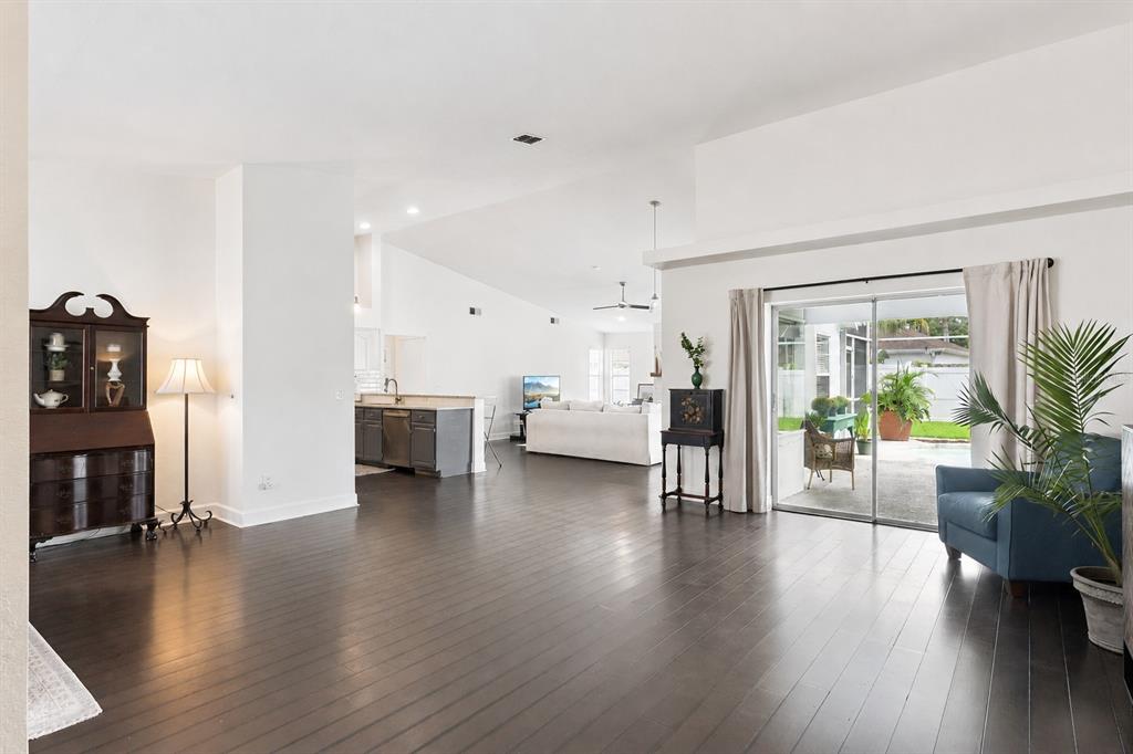 An open-concept living area features dark hardwood floors, white walls, and a sliding glass door — 13627 DORNOCH DRIVE, ORLANDO, FL