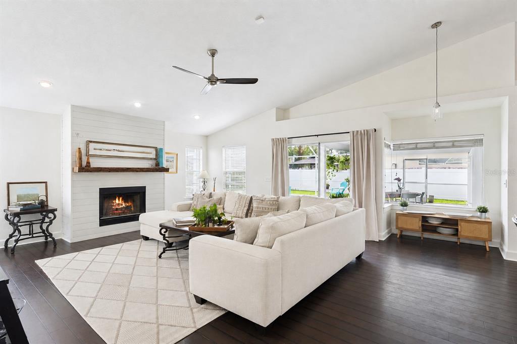 A bright living room features a white fireplace, sectional sofa, and dark hardwood flooring — 13627 DORNOCH DRIVE, ORLANDO, FL