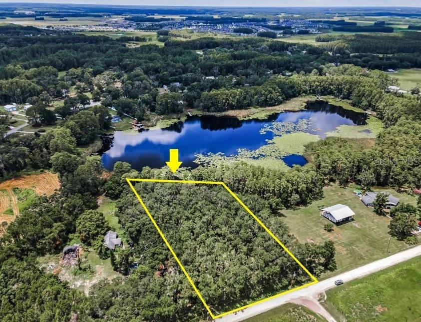 An aerial view shows a wooded, rectangular lot bordering a lake with a yellow outline — 4635 COBB ROAD, LAND O LAKES, FL
