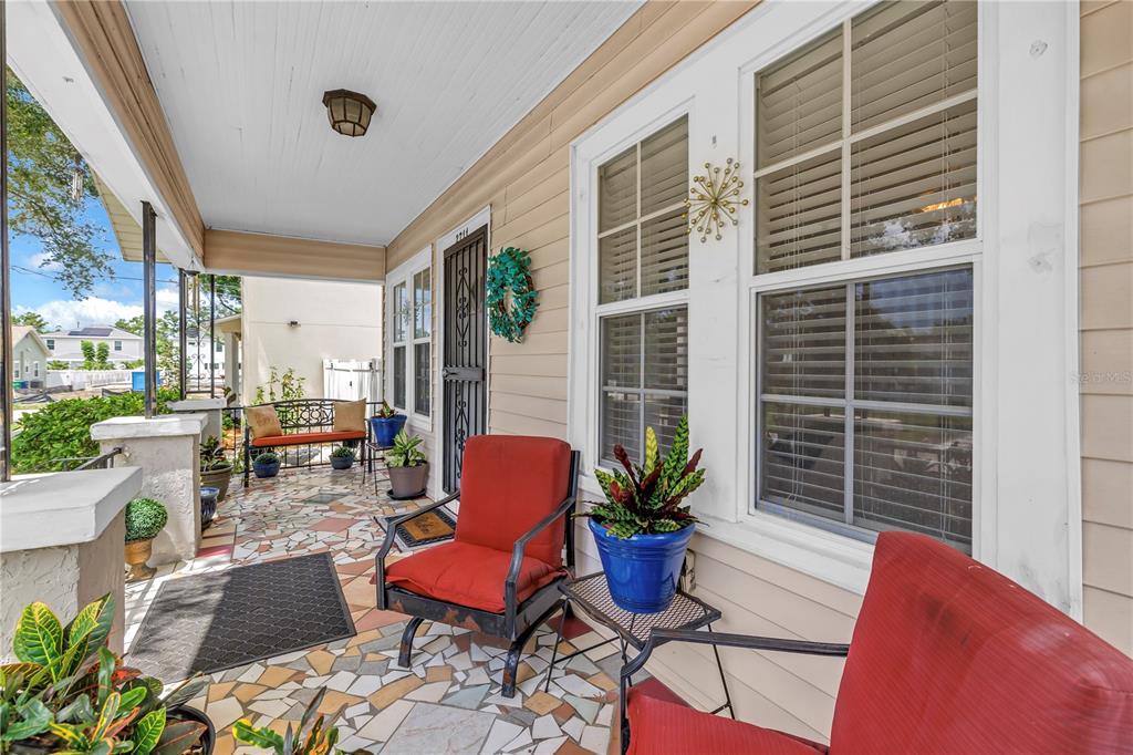 A covered front porch features a mosaic tile floor, red patio chairs, and potted plants — 2711 W FIG STREET, TAMPA, FL