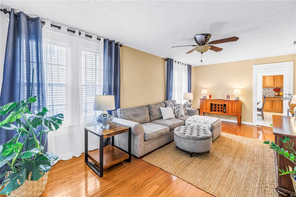 A living room features a gray sectional sofa, a round ottoman, and hardwood flooring — 2711 W FIG STREET, TAMPA, FL