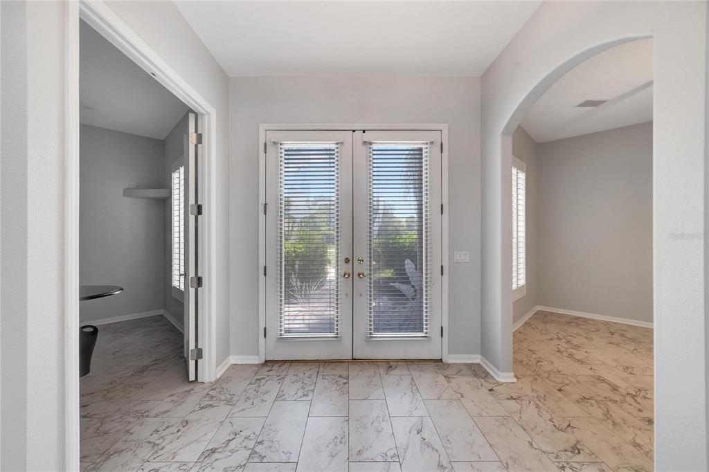 A foyer with marble-look tile flooring features double glass doors and two arched entryways — 17904 CACHET ISLE DRIVE, TAMPA, FL