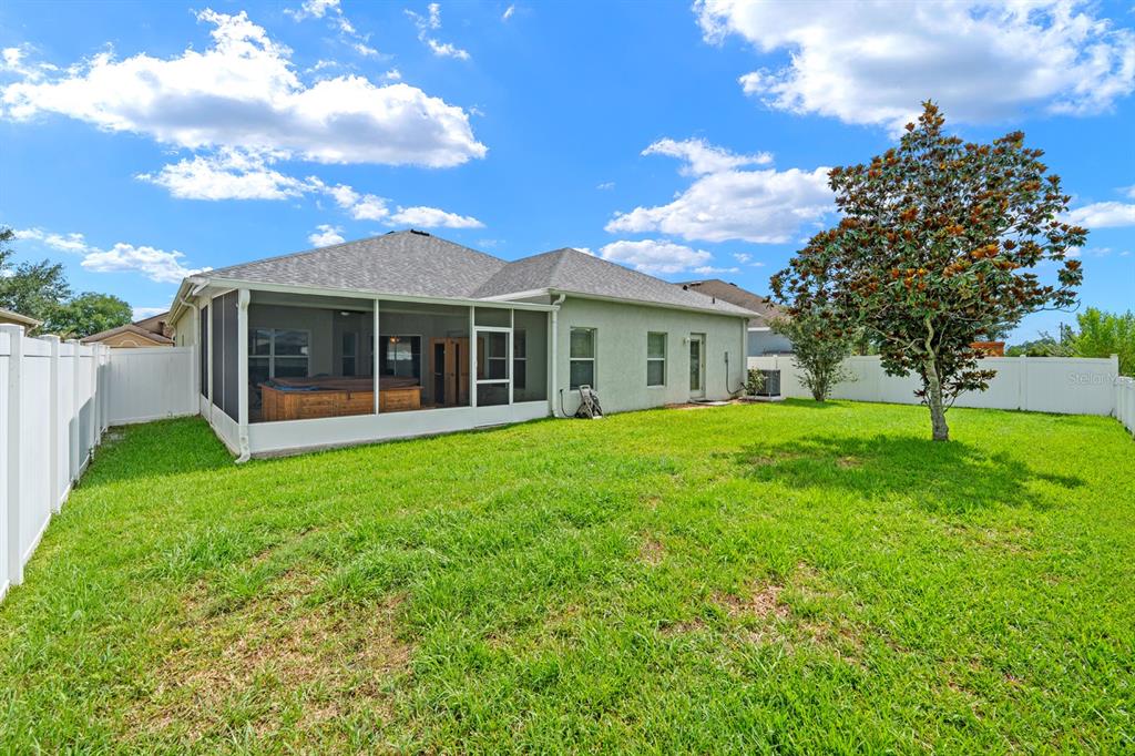 A single-story house with a three-car garage and a concrete driveway under a blue sky — 6751 BOULDER RUN LOOP, WESLEY CHAPEL, FL