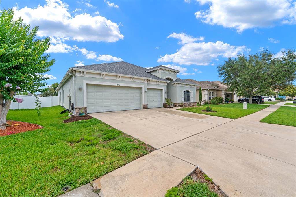 A single-story house with a three-car garage, stone accents, and a front lawn — 6751 BOULDER RUN LOOP, WESLEY CHAPEL, FL