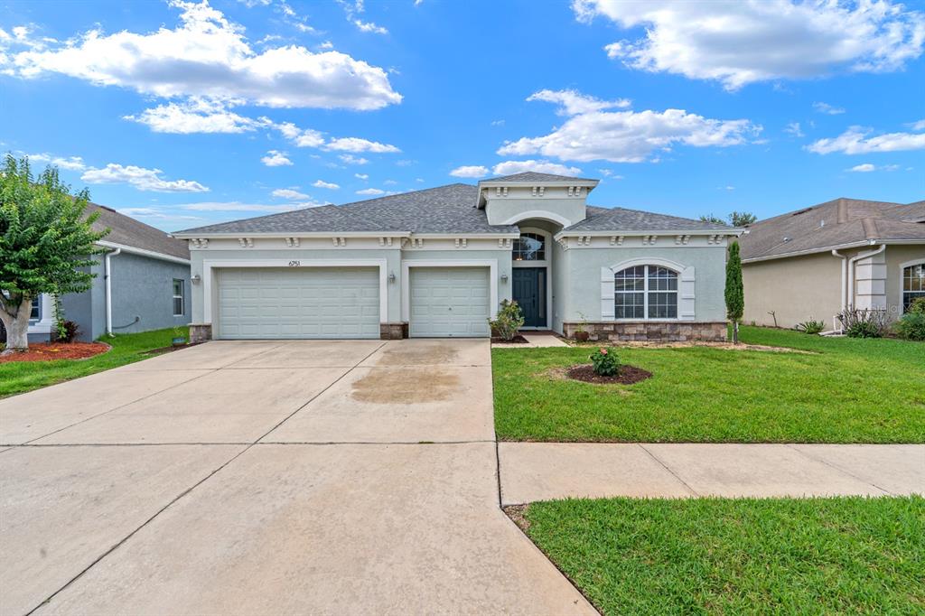 A grassy backyard features a white vinyl fence, a small tree, and a pond view — 6751 BOULDER RUN LOOP, WESLEY CHAPEL, FL