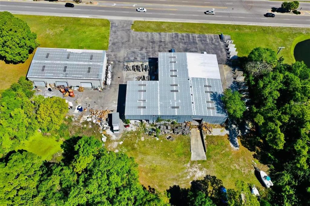 An aerial view shows two industrial warehouse buildings with metal roofs and a parking lot — 2398 63RD AVENUE E, BRADENTON, FL