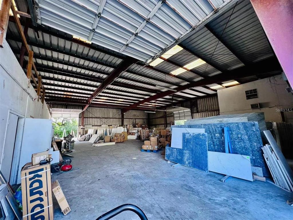 A large, open warehouse space features high ceilings, exposed metal beams, and stored stone slabs — 2398 63RD AVENUE E, BRADENTON, FL