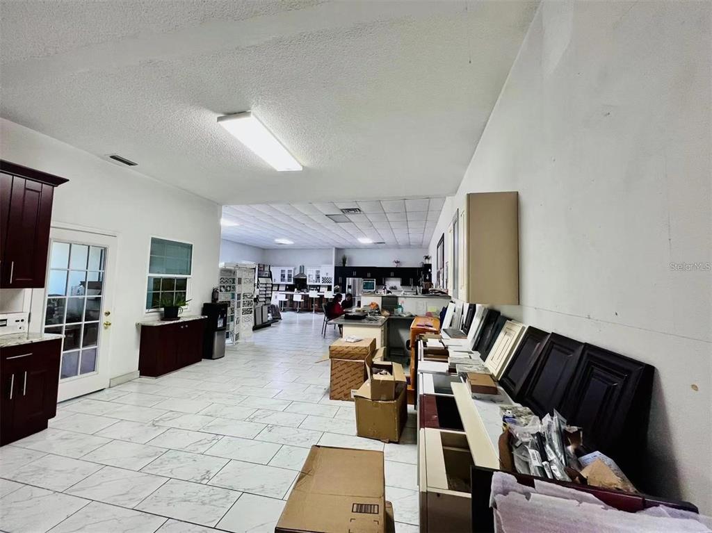 A commercial showroom features white tiled floors, drop ceilings, and various kitchen cabinet displays — 2398 63RD AVENUE E, BRADENTON, FL