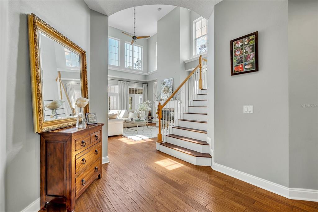 A foyer with wood floors, a wooden chest, a mirror, and stairs leading to a living area — 807 OAK SHADOWS ROAD, CELEBRATION, FL