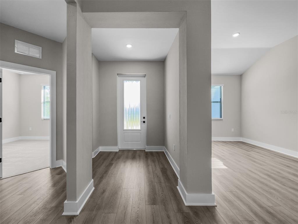 An entryway with light gray walls, wood-look flooring, and a white front door — 2411 GALLAGHER ROAD, DOVER, FL