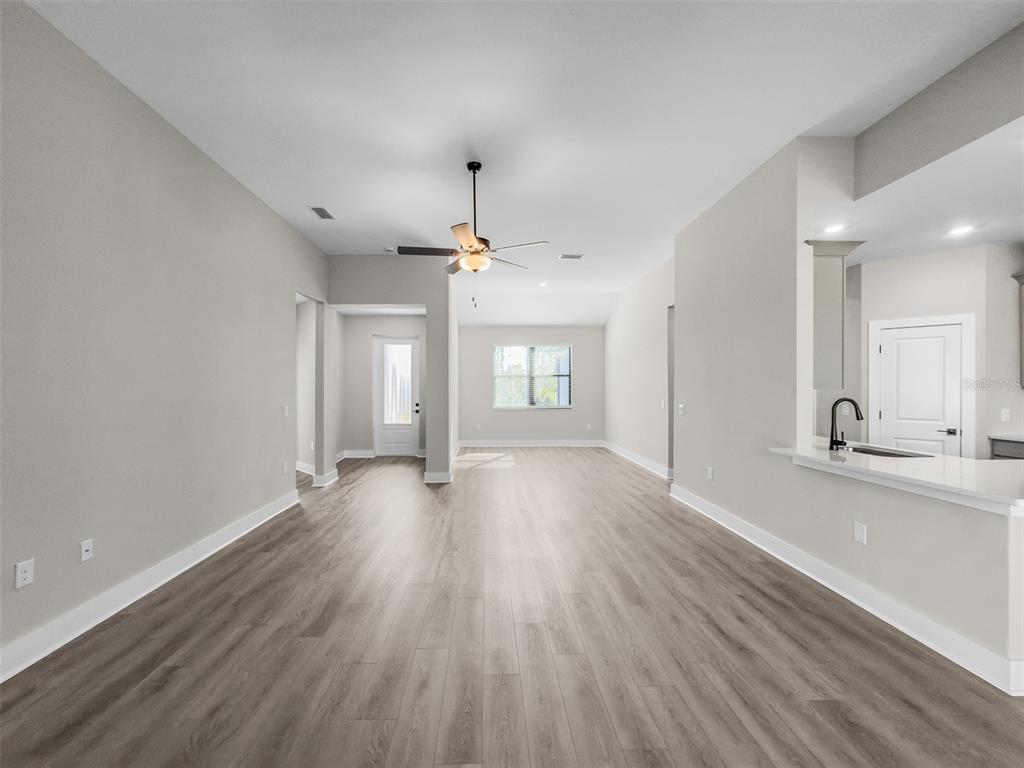 An open-concept living area features light gray walls, wood-look flooring, and a ceiling fan — 2411 GALLAGHER ROAD, DOVER, FL