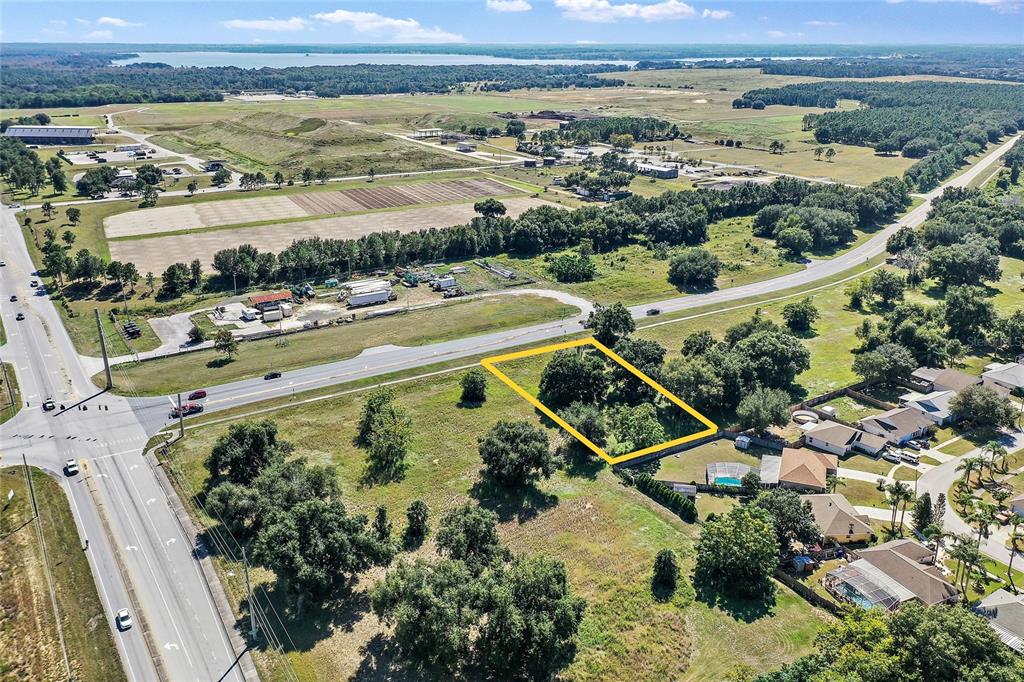 An aerial view shows a vacant, tree-filled lot outlined in yellow near a highway — CR 448 Lot 1, TAVARES, FL