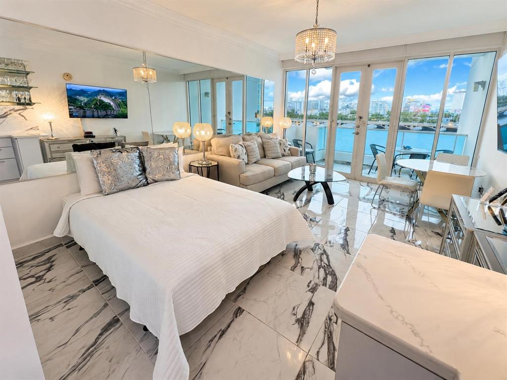 A studio apartment features a bed, sofa, marble floors, and a balcony overlooking the water — 1 CALLE SAN GERONIMO UNIT 319, SAN JUAN, PR