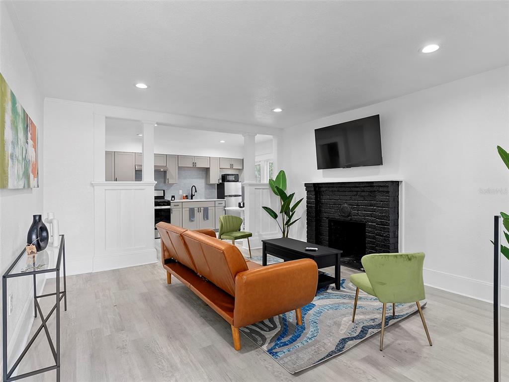 A living room with a black brick fireplace, brown sofa, and an open kitchen — 412 E HARWOOD STREET UNIT 1, ORLANDO, FL