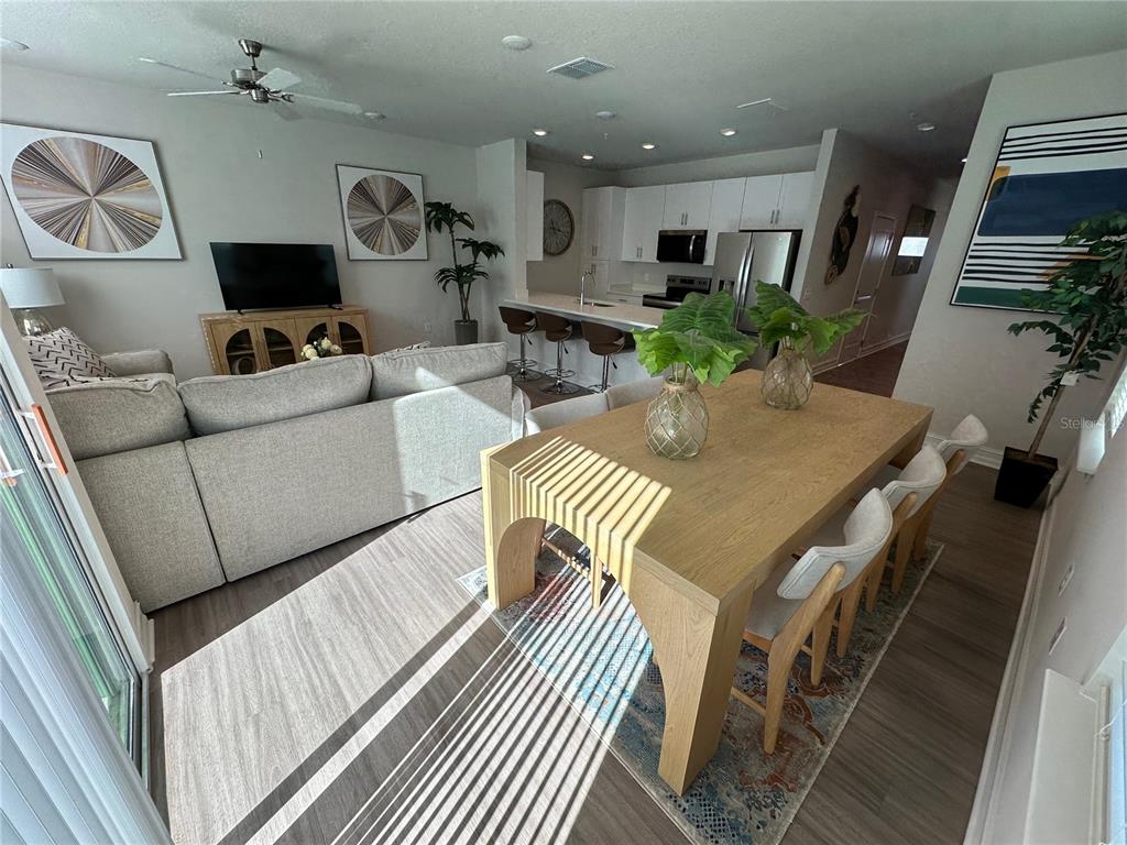 An open-concept living and dining area features a light wood table, sectional sofa, and kitchen — 1057 E CAROLINE STREET, TAVARES, FL