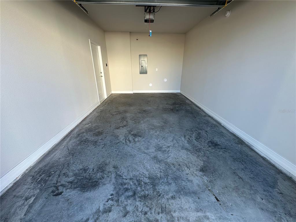 An empty garage with a concrete floor, white walls, and a central electrical panel — 1057 E CAROLINE STREET, TAVARES, FL