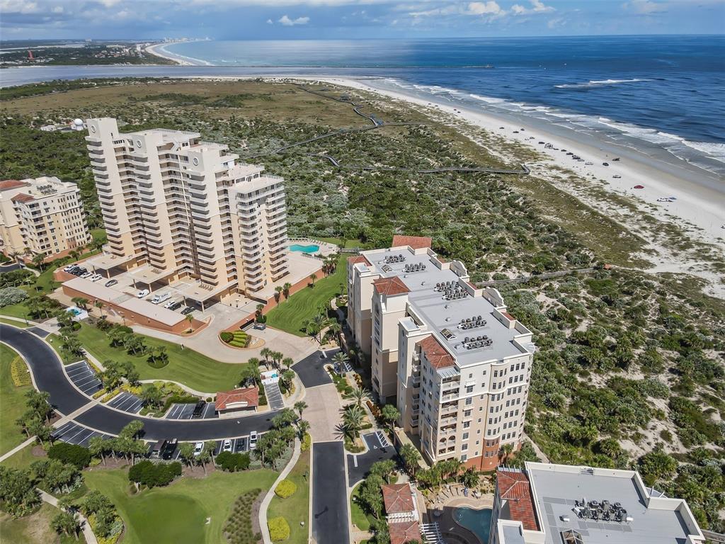 An aerial view shows two large residential buildings situated near a sandy beach and ocean — 255 MINORCA BEACH WAY UNIT 205, NEW SMYRNA BEACH, FL