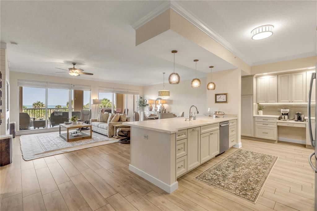 An open-concept kitchen and living area with light wood floors, a kitchen island, and balcony views — 255 MINORCA BEACH WAY UNIT 205, NEW SMYRNA BEACH, FL