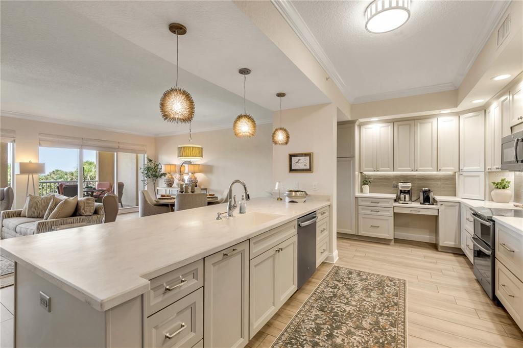 A kitchen with light-colored cabinets, a large island with a sink, and an adjacent living area — 255 MINORCA BEACH WAY UNIT 205, NEW SMYRNA BEACH, FL