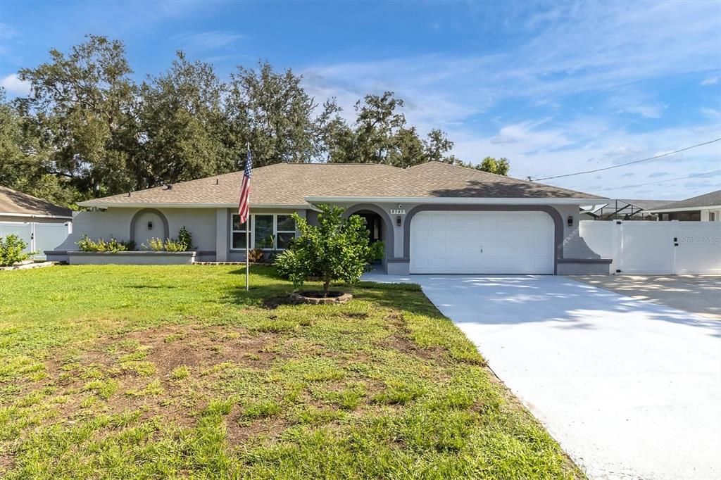 A single-story house with a gray exterior, a white garage door, and a front lawn — 8345 APPLE ORCHARD ROAD, SPRING HILL, FL
