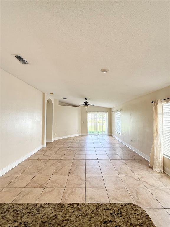An open-concept living area features light-colored tile flooring, beige walls, and a sliding glass door — 7731 CARRIAGE POINTE DRIVE, GIBSONTON, FL
