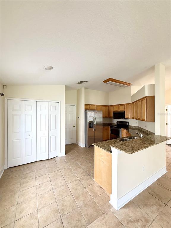A kitchen with light wood cabinets, granite countertops, stainless steel appliances, and tile flooring — 7731 CARRIAGE POINTE DRIVE, GIBSONTON, FL