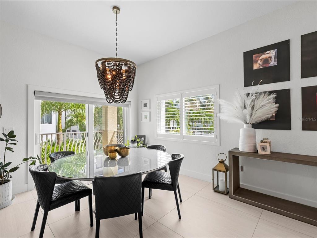 A dining room features a glass table, black chairs, a beaded chandelier, and a console table — 138 175TH AVENUE E, REDINGTON SHORES, FL