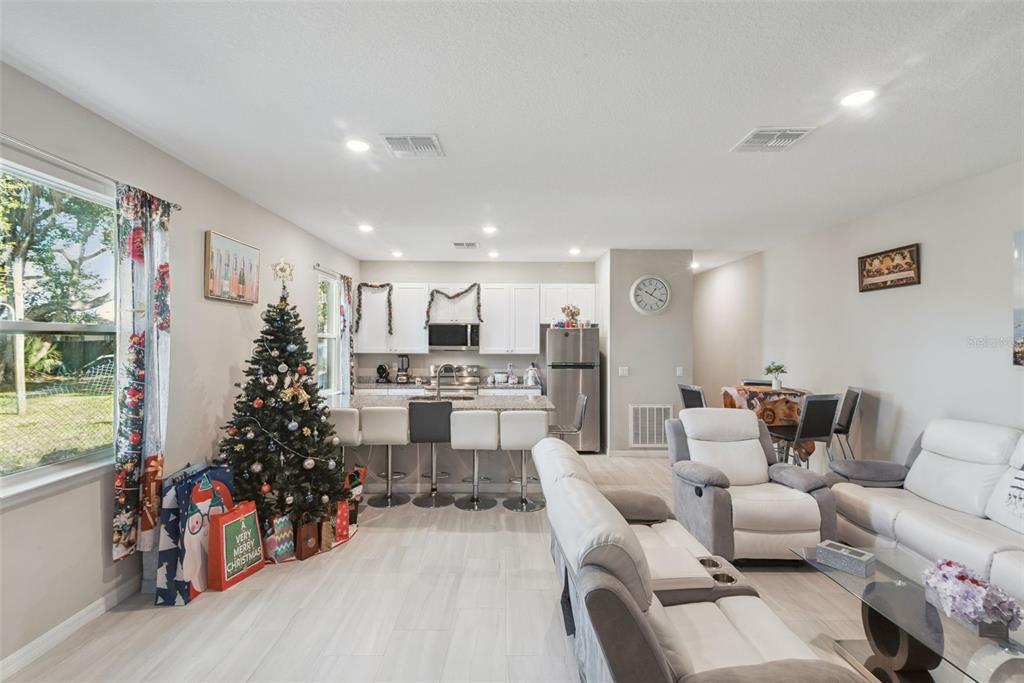 An open-concept living room and kitchen featuring a Christmas tree, white cabinetry, and tile flooring — 1021/1023 TITCOMB STREET, EUSTIS, FL